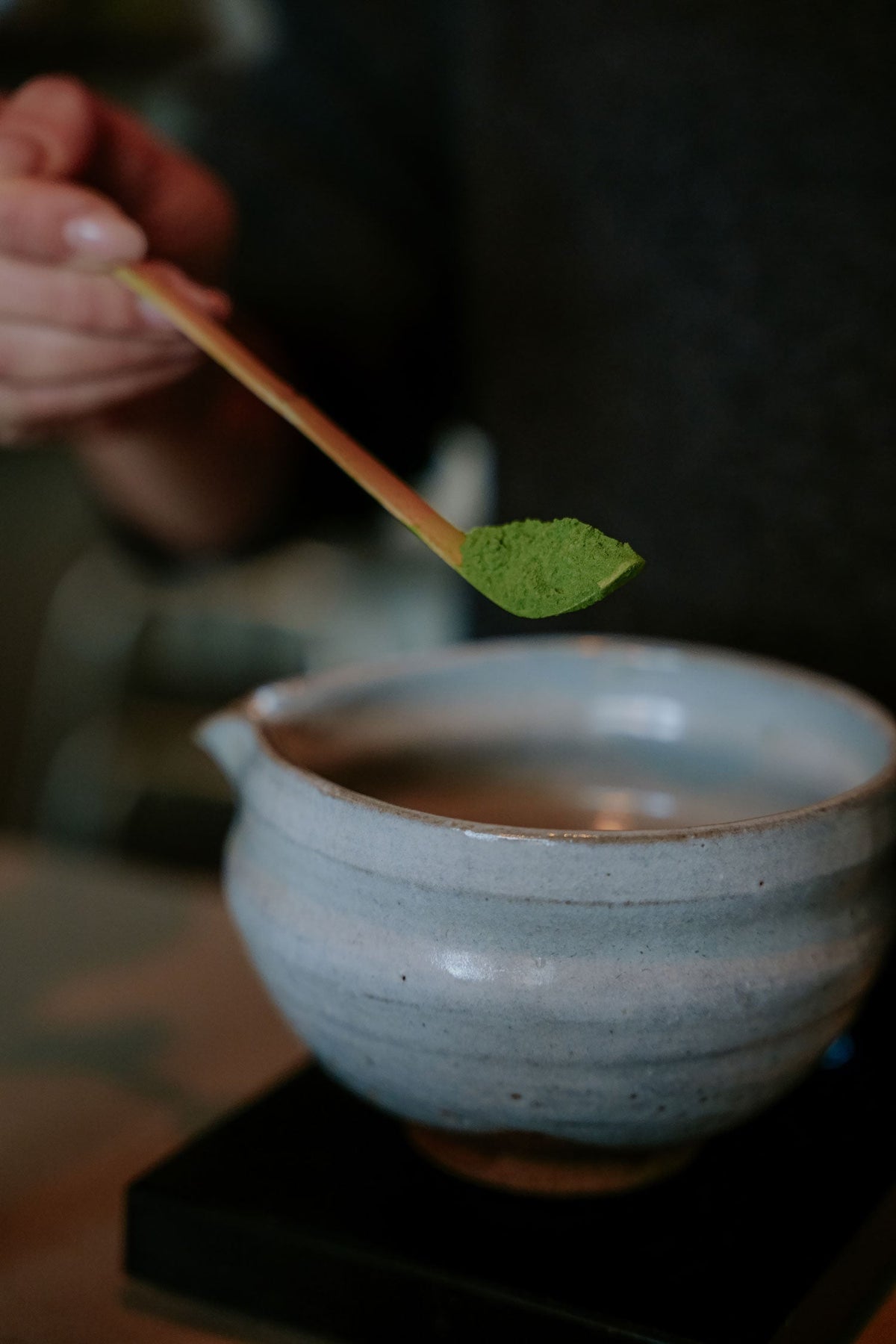 Matcha powder and a bamboo chasen whisk, used in traditional Japanese tea preparation.