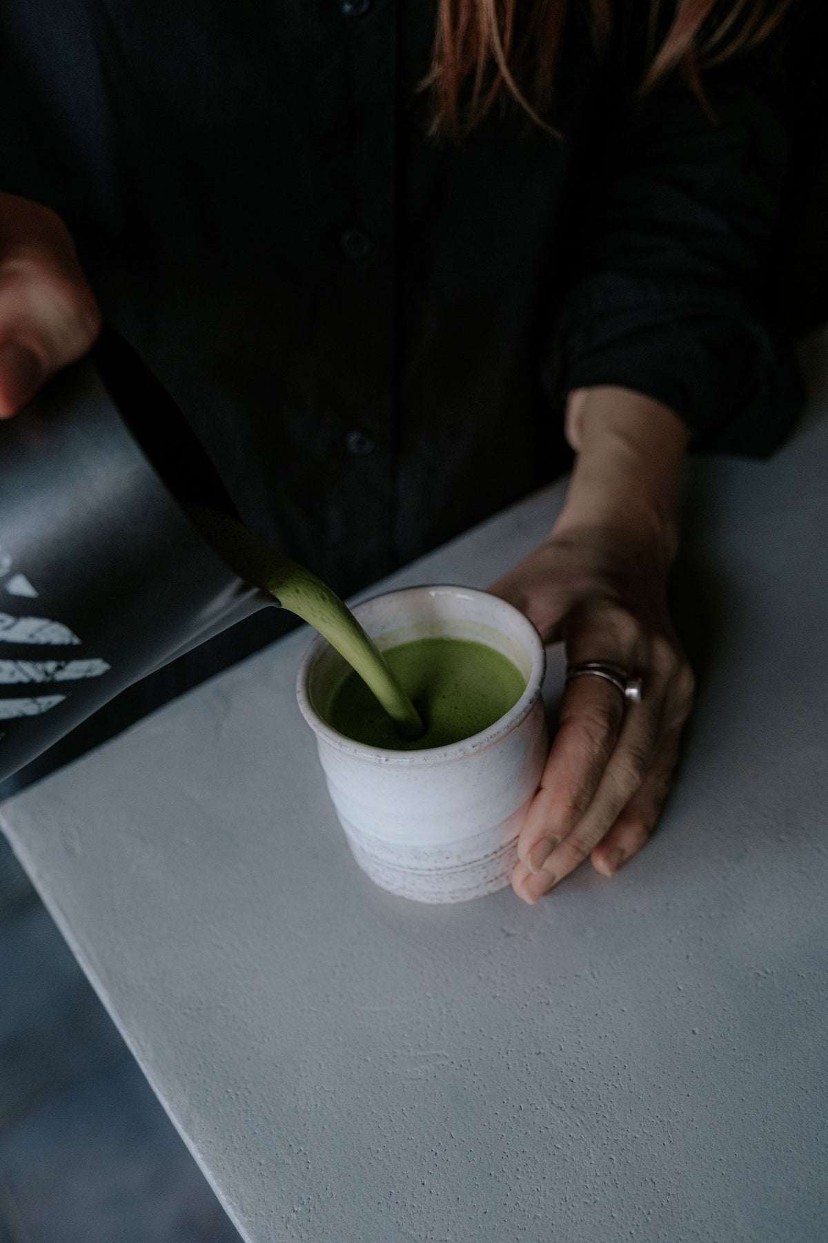 A matcha latte in a clear glass, made with Kūkai matcha and milk.