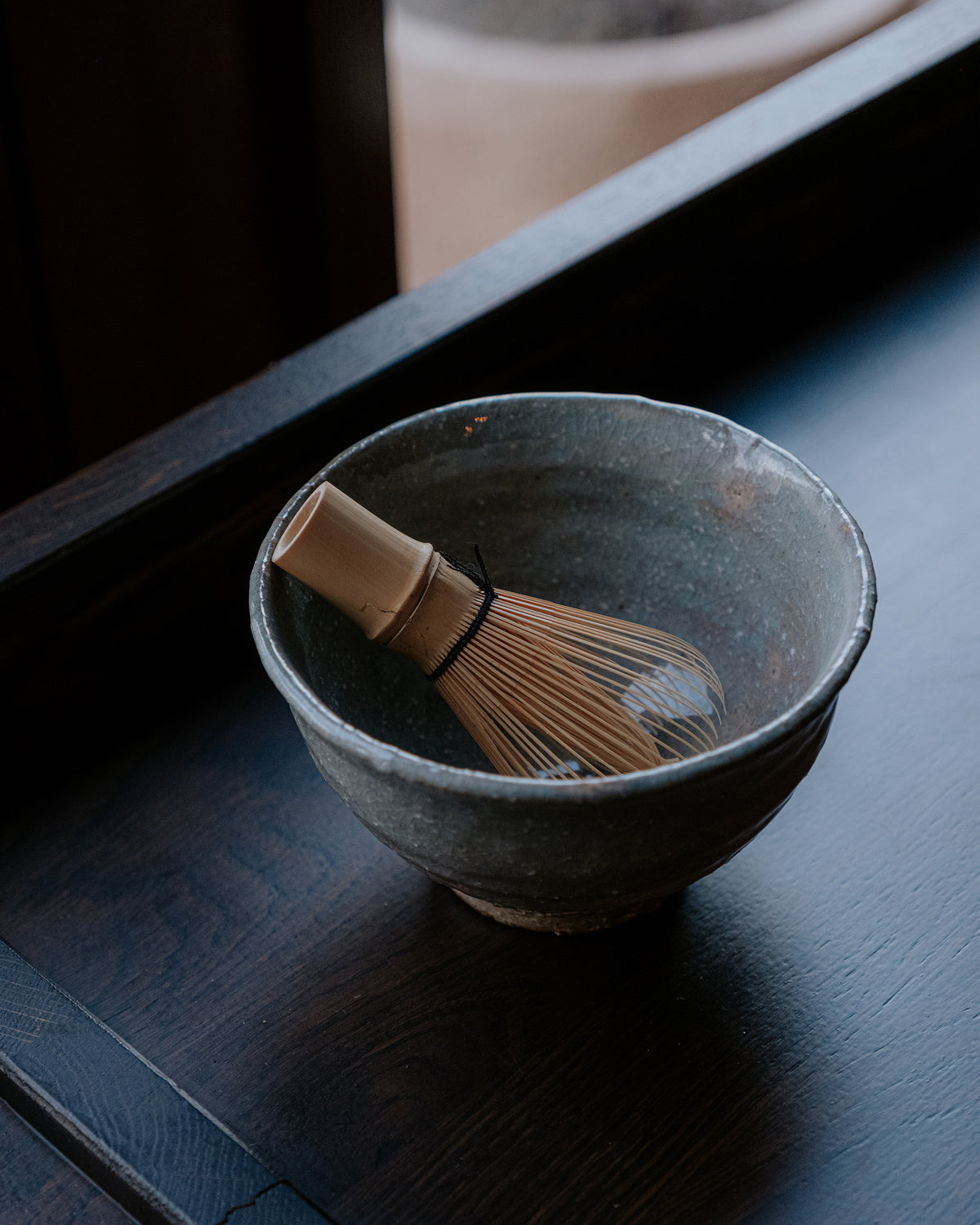 Bamboo whisk resting in matcha bowl
